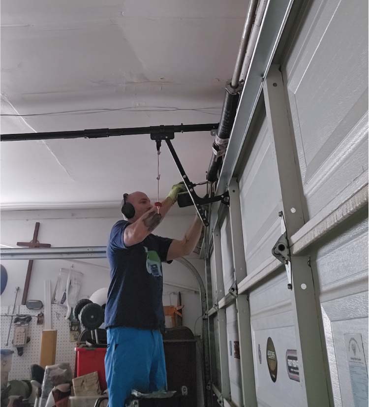 Central Coast Garage Doors 24/7 owner Cory Lewis performing professional garage broken spring repair and adjustment in a San Luis Obispo residential garage
