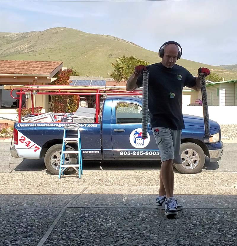 Professional technician from Central Coast Garage Doors 24/7 performing garage door repair in paso robles, california. The company service truck with license #1049595 is visible in the background against the rolling California hills