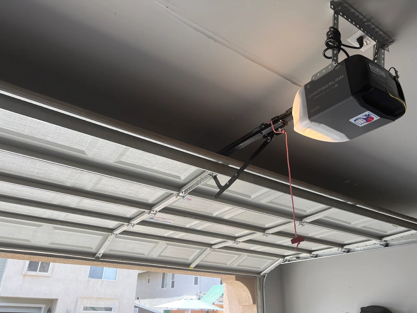 A detailed view of the overhead tracks and lifting cables during a professional garage door repair to restore safety and balance.